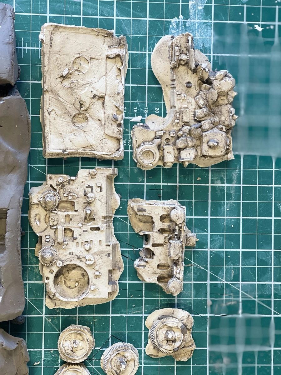 Casts of Walkman parts in clay and plaster, on a cutting mat